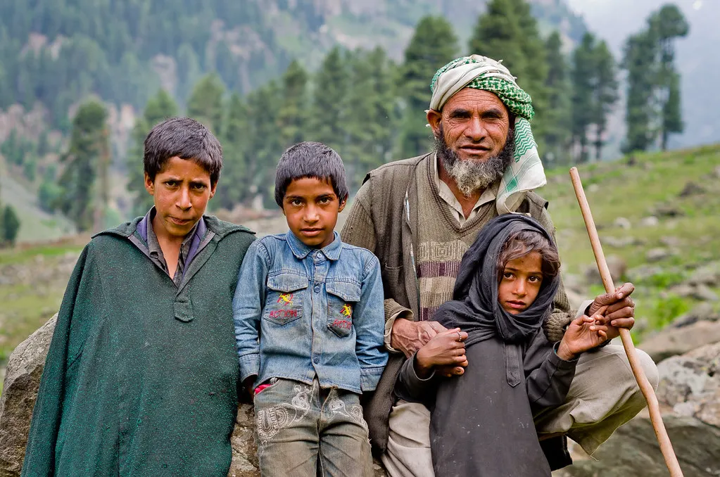 A shepherd family standing together in a mountain meadow